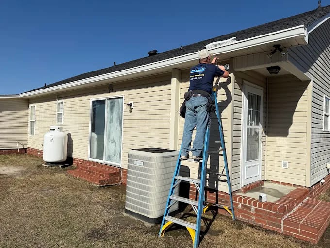 All Clean Rain Gutters installer on a ladder fitting a white seamless gutter along the eaves