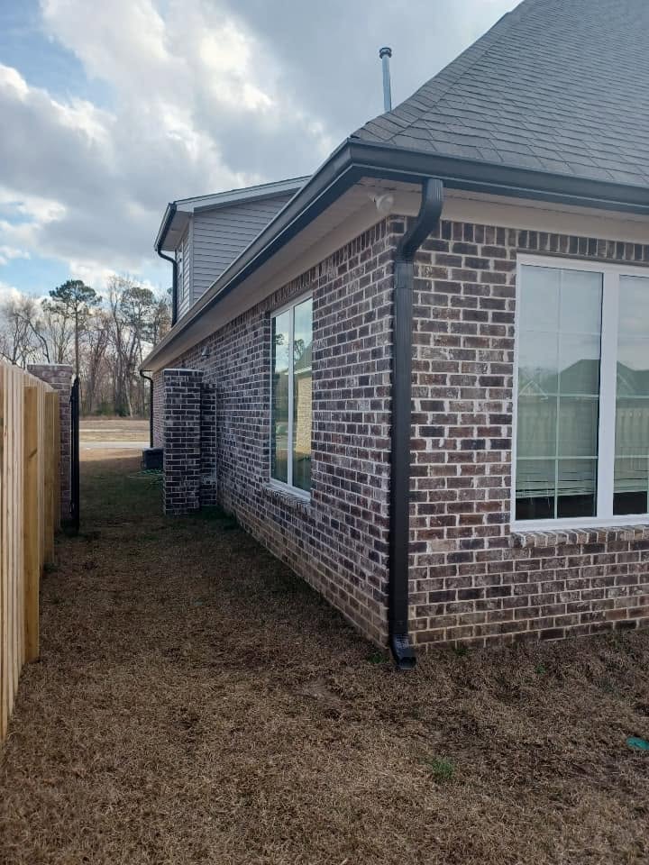 Black downspout running down the corner of a brick home