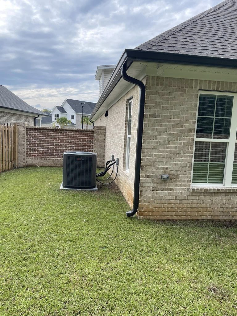 Black seamless gutter and downspout on a light brick home