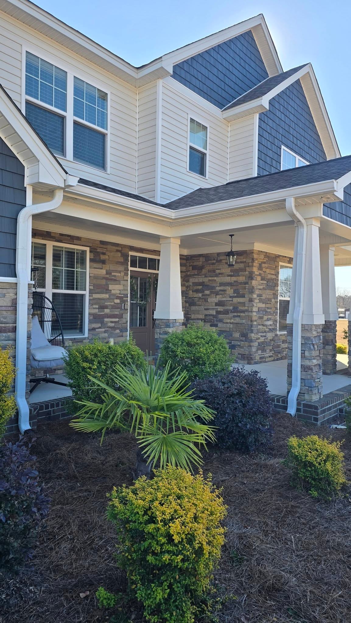 Stone and shingle craftsman home with white seamless gutters and downspouts
