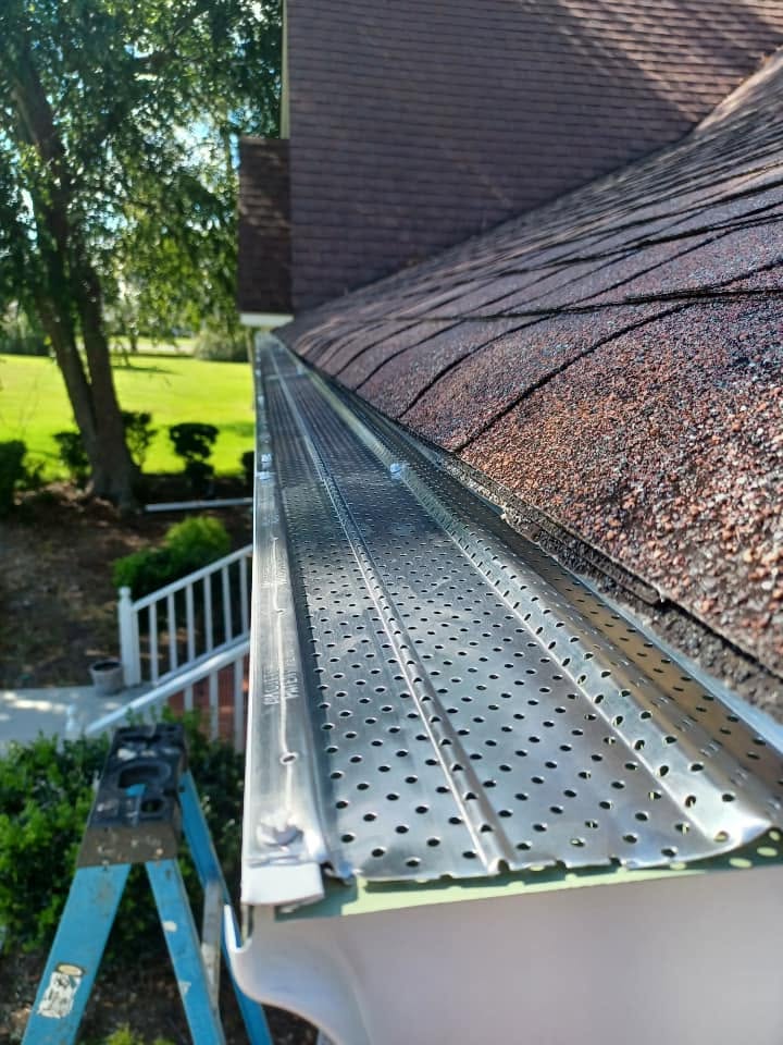Perforated aluminum leaf guard installed over a gutter on a shingle roof