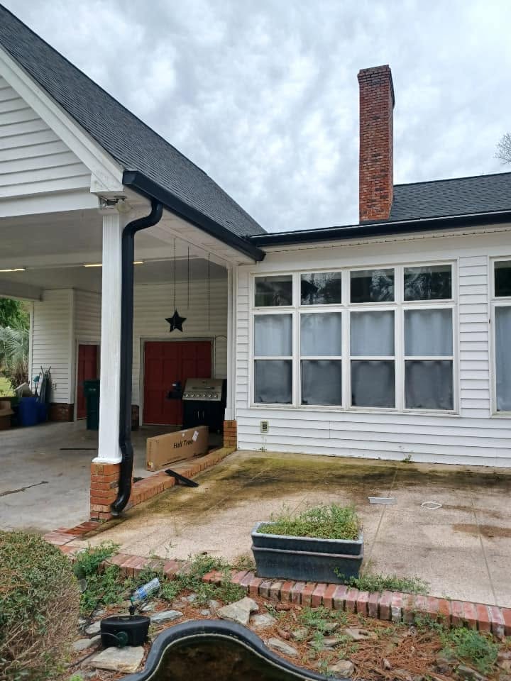 Older home with a replacement black downspout beside the covered patio