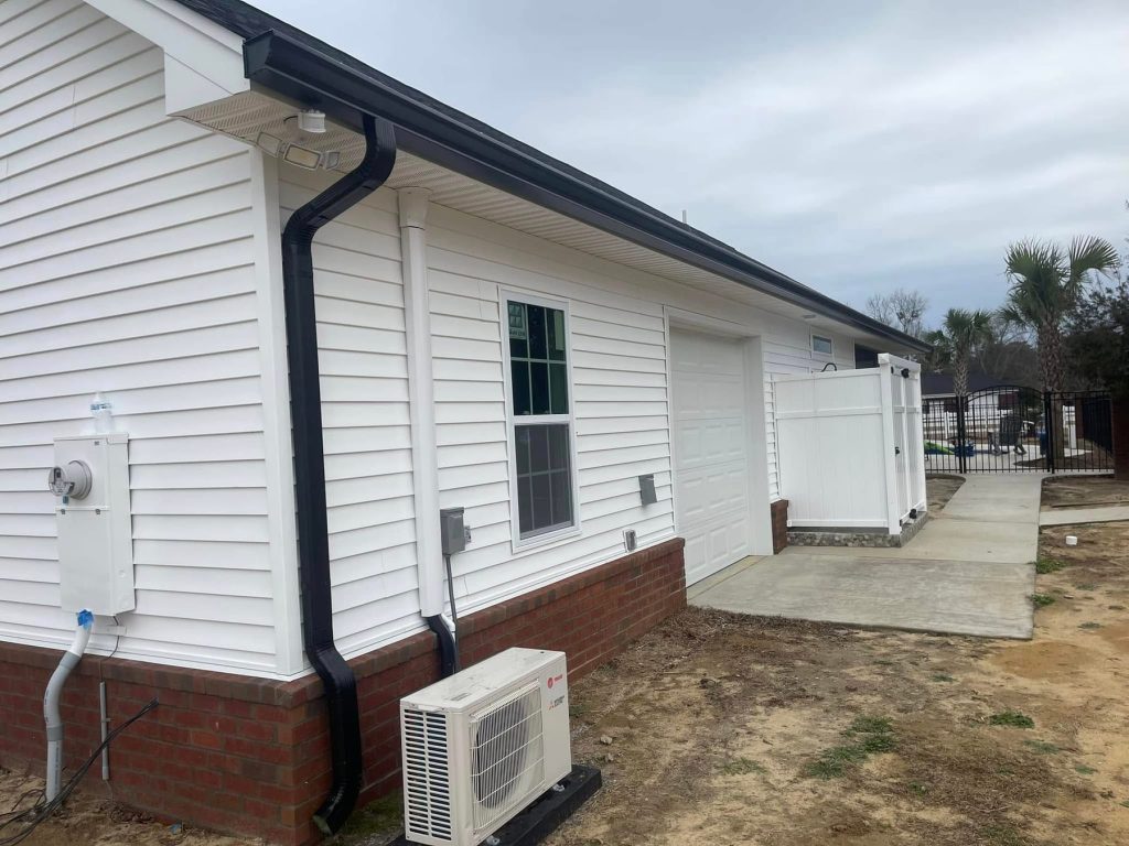 White sided home with black seamless gutter and downspout beside the garage